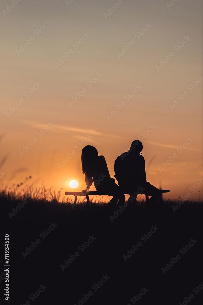 silhouette of couple sitting on a bench at sunset silhouette of couple sitting on a bench at sunset