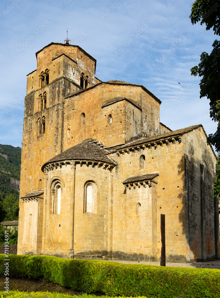 View of impressive ancient Santa Maria church, Romanesque style building in ashlar masonry, former Benedictine nunnery located in spanish village of Santa Cruz de la Seros on sunny summer day, Aragon
