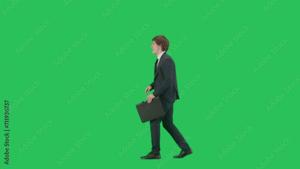 Profile view of male model in suit isolated on chroma key green screen background. Positive young businessman in blue suit walking having fun. Profile view of male model in suit isolated on chroma key green screen background. Positive young businessman in blue suit walking having fun.
