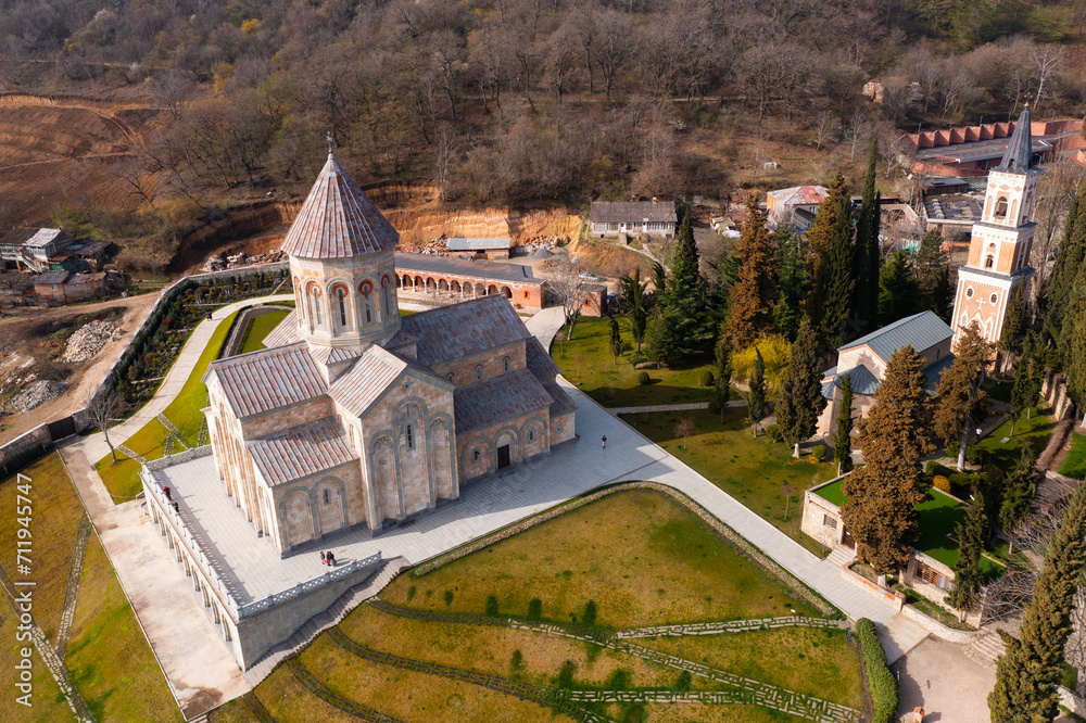 Scenic spring aerial view of monastic complex of Bodbe nunnery on hillside among tall Cypress trees with Church of St. Nino on sunny day, Sighnaghi, Georgia