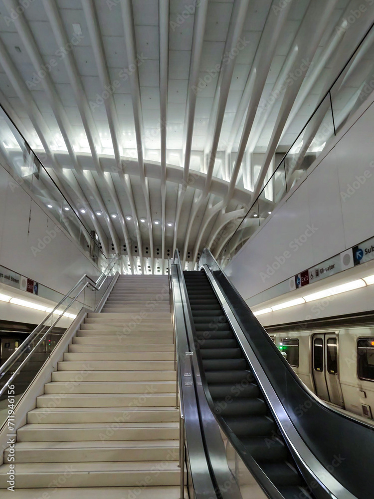 Descending into the heart of New York's World Trade Center Station, the escalator provides a sleek transition between the bustling city above and the serene, modern hallways below. Trains to Jersey Descending into the heart of New York's World Trade Center Station, the escalator provides a sleek transition between the bustling city above and the serene, modern hallways below. Trains to Jersey