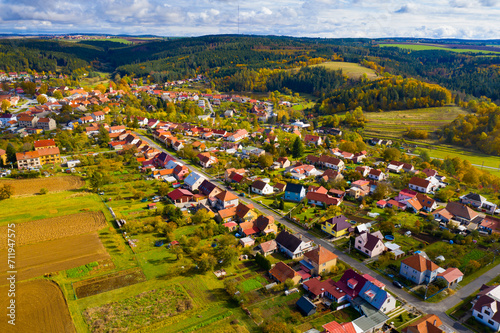 Picturesque aerial view of small Czech village Ostrov u Macochy surrounded by green and orange trees and fields