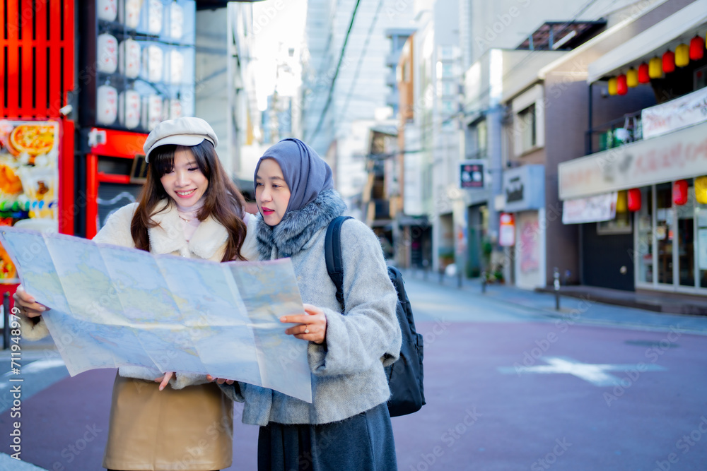 woman girl tourist Two Asian friends but different religions, one of whom is a Muslim girl. Looking at the tour map View information on traveling in Japan. with fun She is traveling in the city area.