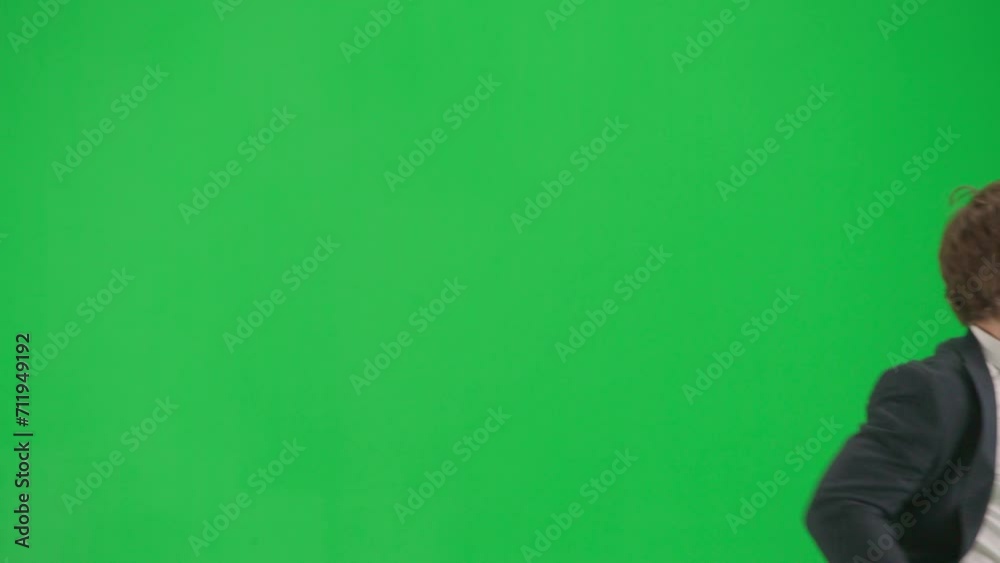 Portrait of male model in suit isolated on chroma key green screen background. Close up shot businessman in suit checks time on smartphone and runs.