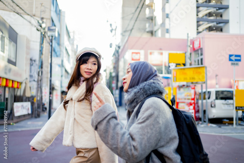 woman girl tourist Two Asian friends but different religions, one of whom is a Muslim girl. Walking tour of the city, city view, traveling in Japan. with fun She is traveling in the city area. © maya1313