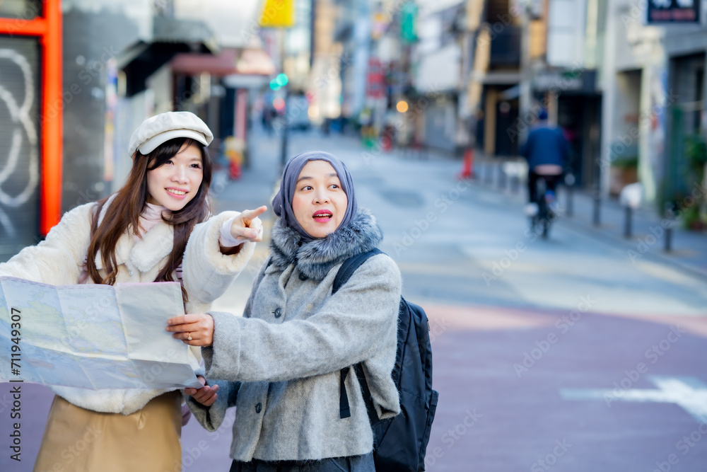 woman girl tourist Two Asian friends but different religions, one of whom is a Muslim girl. Looking at the tour map View information on traveling in Japan. with fun She is traveling in the city area. woman girl tourist Two Asian friends but different religions, one of whom is a Muslim girl. Looking at the tour map View information on traveling in Japan. with fun She is traveling in the city area.
