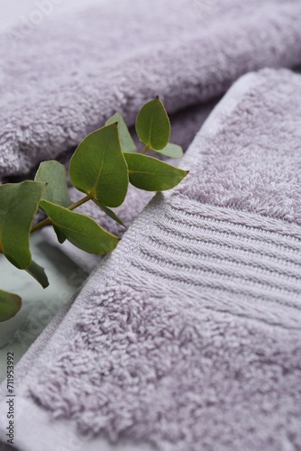 Violet terry towels and eucalyptus branch on table, closeup