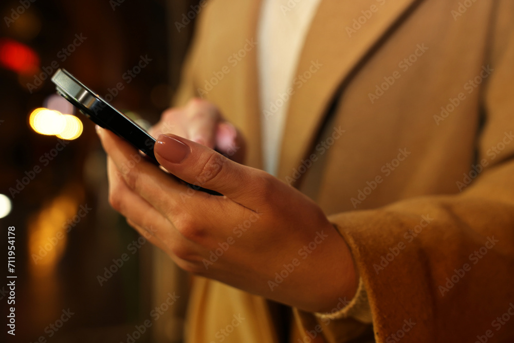 Woman using smartphone on blurred background, closeup