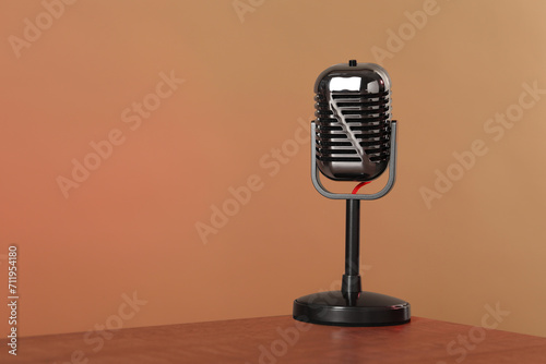 Vintage microphone on table against color background, space for text. Sound recording and reinforcement