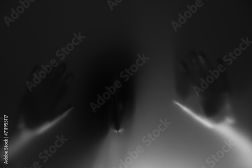 Silhouette of creepy ghost behind glass against grey background photo