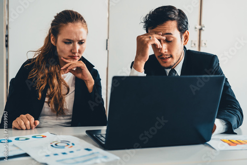 Unhappy serious businessman and businesswoman working using laptop computer on the office desk. Bad business crisis situation and bankruptcy concept. uds photo
