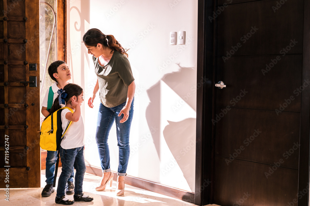 Latin mother receives her children at the door of her home and talks with them about her trip.