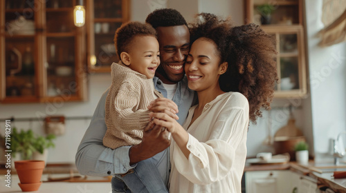 Happy family: full body delighted diverse parents playing and dancing with son in cozy kitchen on weekend day at home photo