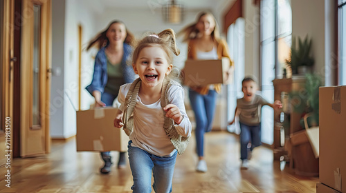 Happy young family with cardboard boxes in new home at moving day concept, excited children running into big modern own house hallway, parents with belongings at background, mortgage loan, relocation photo