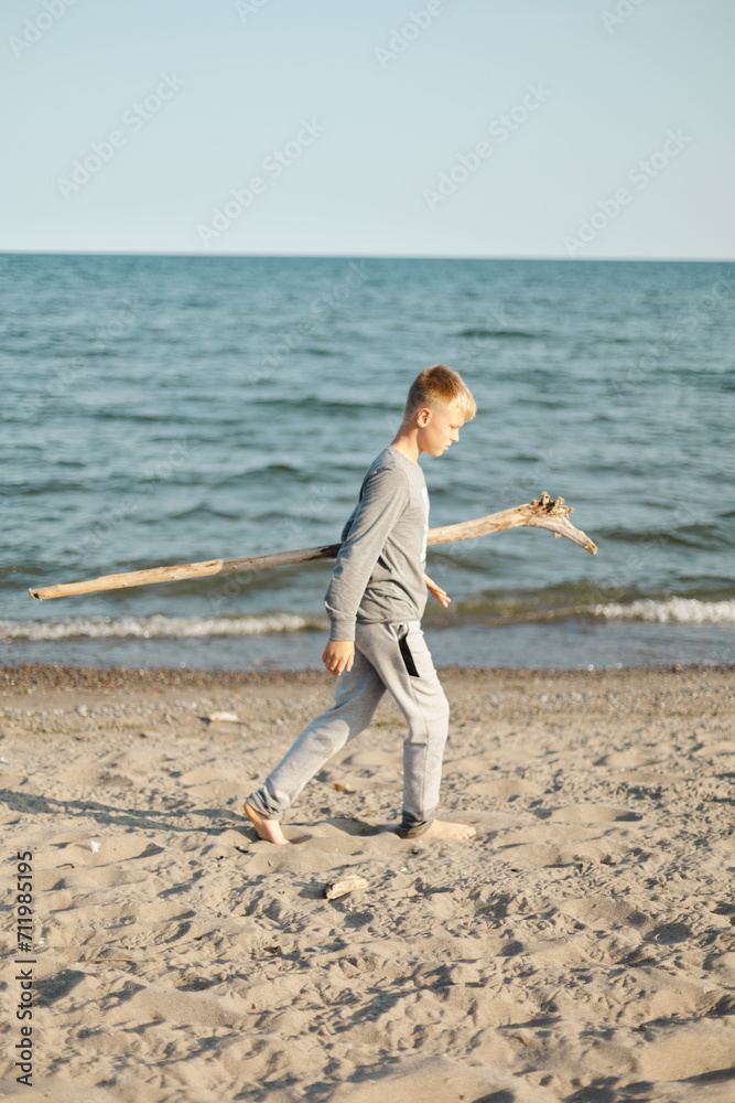 Big boy playing with a log on the sandy beach in Canada 