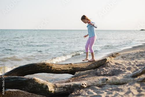 child walking on the tree log on the beach