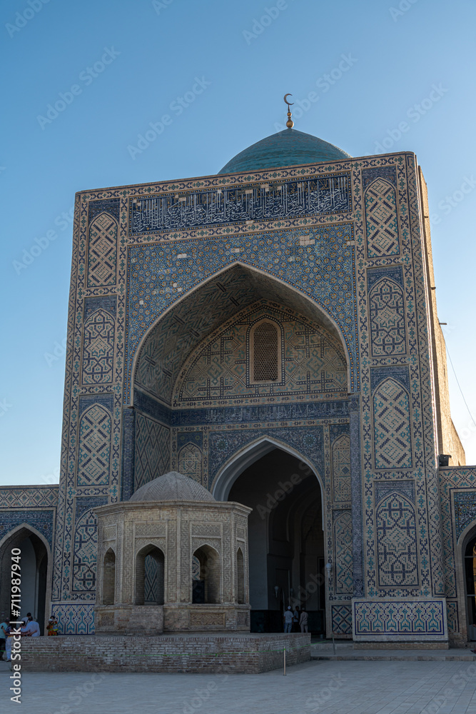 View to Mir i Arab madrassa through old wooden carved door, Bukhara, Uzbekistan