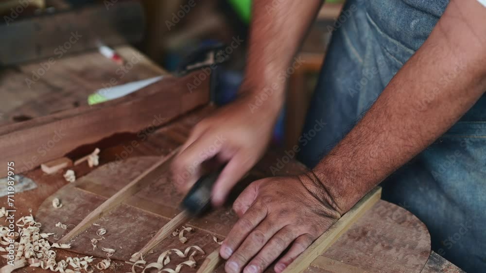 Luthier making a guitar and using traditional tools in workroom with manual tools