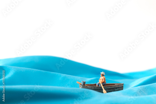 Miniature people   Fisherman in a boat on the waves   World Water Day concept