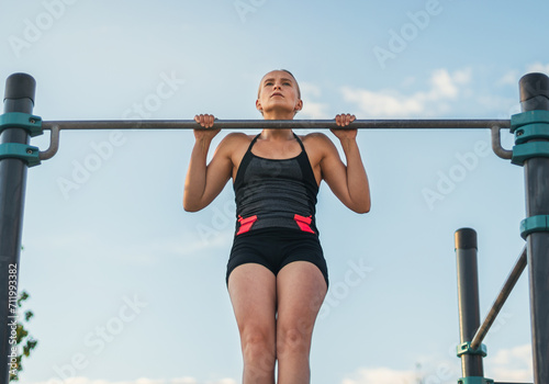 woman athlete doing pull ups on a bar outdoors. calisthenics
