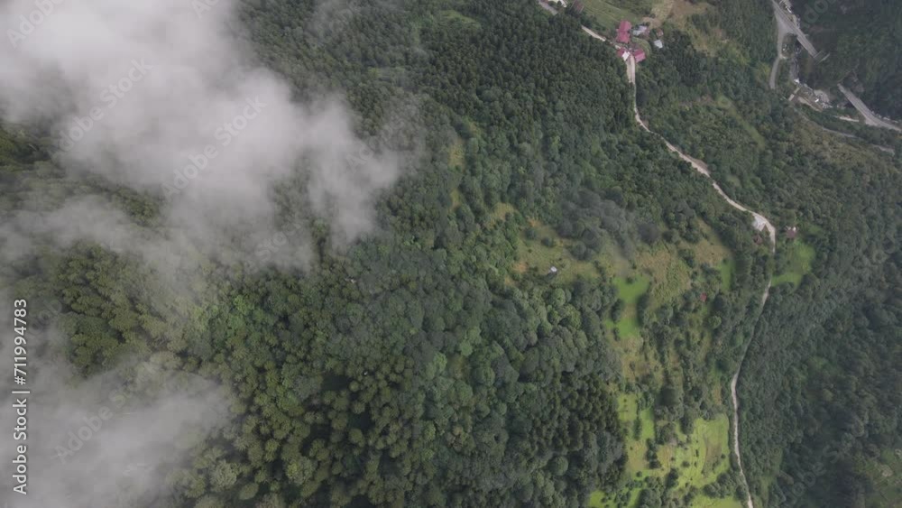 Rural settlement among the green valley, and mountain, viewed by drone through the clouds Rural settlement among the green valley, and mountain, viewed by drone through the clouds