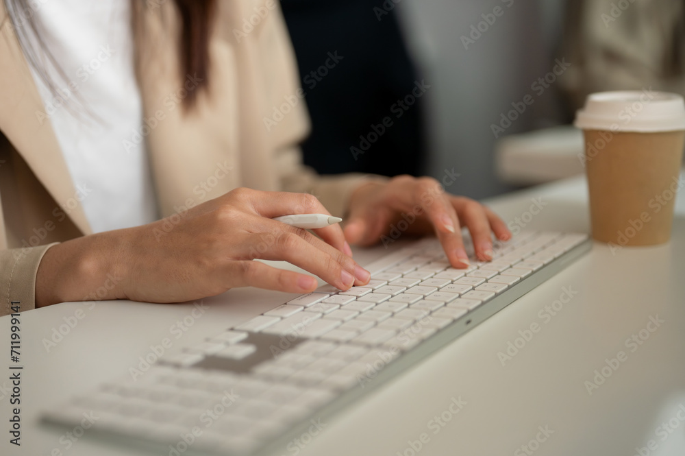 Close-up image of a businesswoman working at her desk in the office, typing on keyboard computer. Close-up image of a businesswoman working at her desk in the office, typing on keyboard computer.