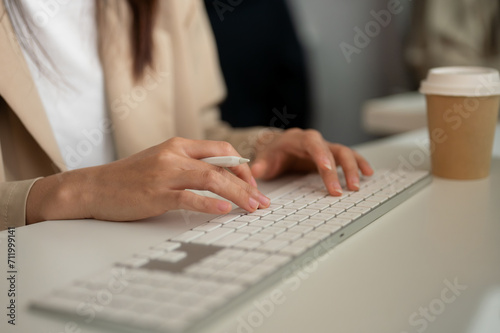 Close-up image of a businesswoman working at her desk in the office, typing on keyboard computer.