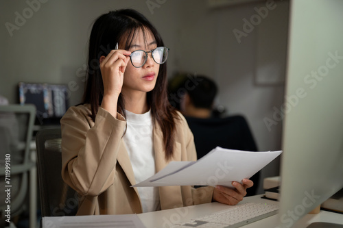 A professional Asian businesswoman is checking online report on computer and working in the office.