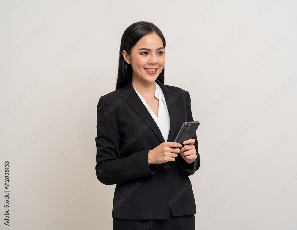 Attractive elegant young asian business woman using cellphone standing on isolated background. Happy Excited young asian female formal black suit holding smartphone contract service with customer Attractive elegant young asian business woman using cellphone standing on isolated background. Happy Excited young asian female formal black suit holding smartphone contract service with customer