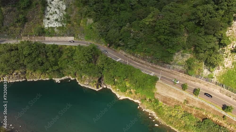 Aerial top down shot of cars on road near river in Wulai Mountains at sunny day, Taiwan - Tourism in village with parking buses