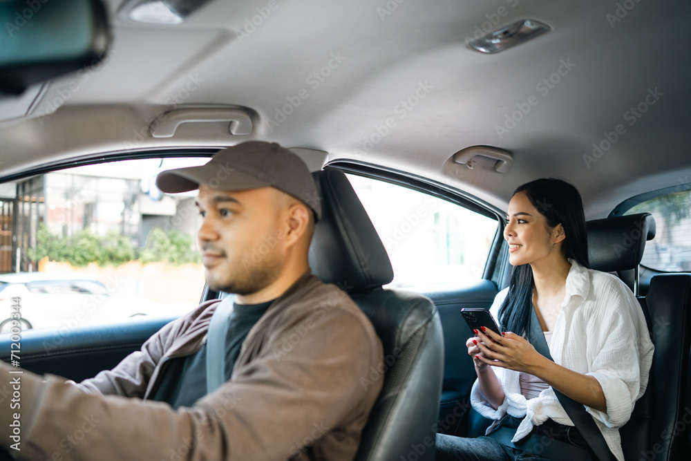 Young asian woman traveler talking with taxi driver explain the route how to travel in direction destination. Passenger showing the direction to taxi driver travel in city. Driver application service Young asian woman traveler talking with taxi driver explain the route how to travel in direction destination. Passenger showing the direction to taxi driver travel in city. Driver application service