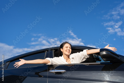 Young beautiful asian business women getting new car. Happy smiling female driving vehicle on the road Sticking her head outta the windshield with sun light. Business woman buying driving new car