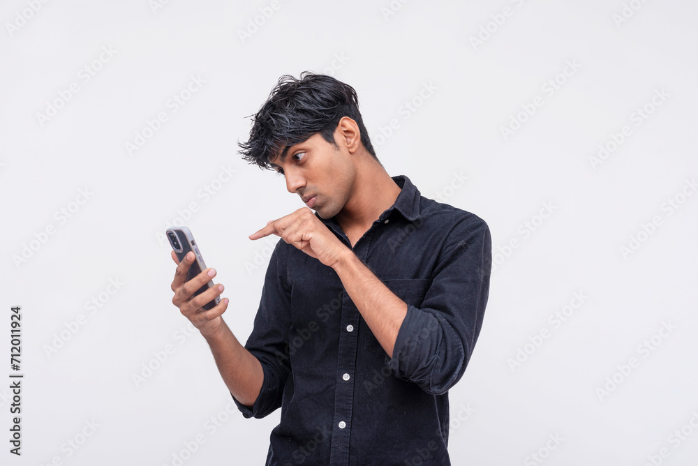 Young man pointing at smartphone screen in disbelief Young man pointing at smartphone screen in disbelief