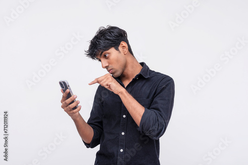 Young man pointing at smartphone screen in disbelief