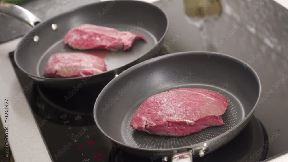 Cooking fried steak, frying beef steaks in a frying pan on the stove in the kitchen Cooking fried steak, frying beef steaks in a frying pan on the stove in the kitchen
