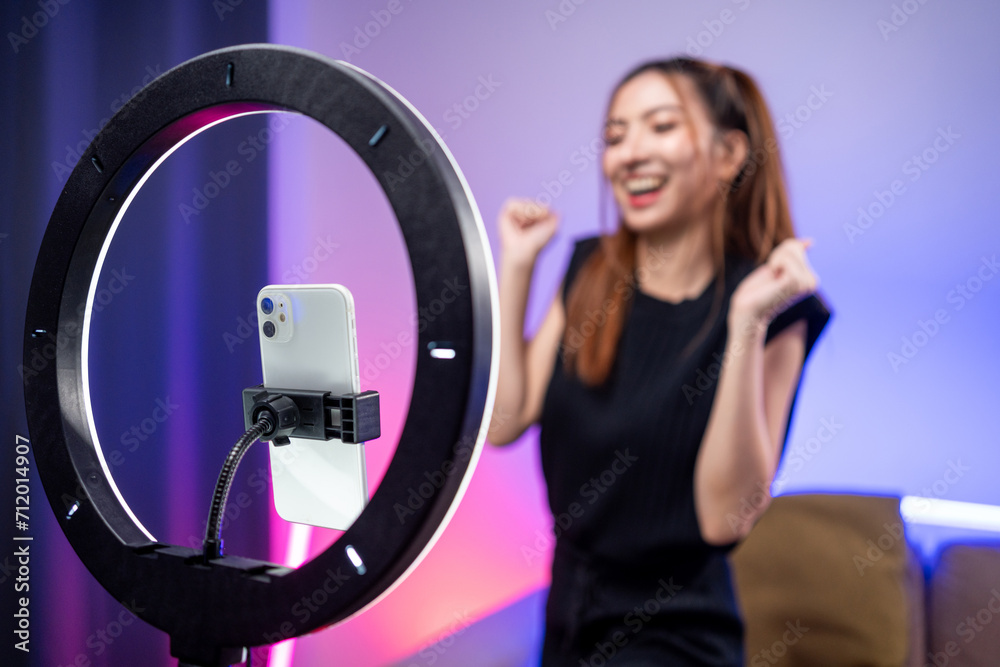 Young trendy influencer asian woman dancing on mobile phone at home in living room with neon light. Creator vlogger talent dancing enjoy hobby content recording show video sharing on social media. Young trendy influencer asian woman dancing on mobile phone at home in living room with neon light. Creator vlogger talent dancing enjoy hobby content recording show video sharing on social media.