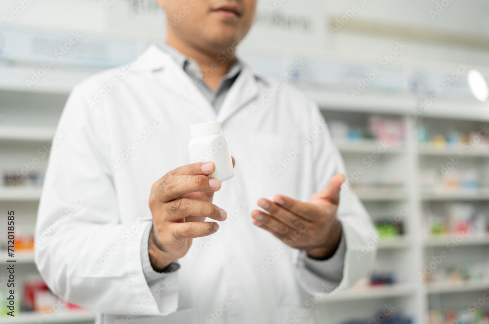 Professional asian man pharmacist checks inventory arrangement of medicine in pharmacy drugstore. Male Pharmacist wearing uniform standing near drugs shelves counter prescription to customers Professional asian man pharmacist checks inventory arrangement of medicine in pharmacy drugstore. Male Pharmacist wearing uniform standing near drugs shelves counter prescription to customers