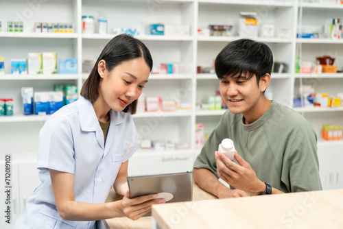 Pharmacist recommends medicines to customers.Taking the questions of medication. Asian female pharmacist giving prescription medications to customers at drugstore shelves.