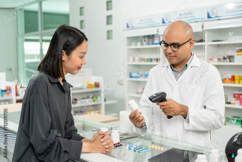 Payment with Barcode scanning to sell medicines. Pharmacist recommends medicines to customers. Professional Asian male pharmacist selling medications to female patient at drugstore shelves.