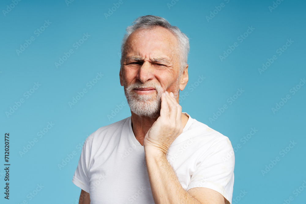 Portrait of mature 60 years old man wearing white casual t shirt with closed eyes touching face Portrait of mature 60 years old man wearing white casual t shirt with closed eyes touching face