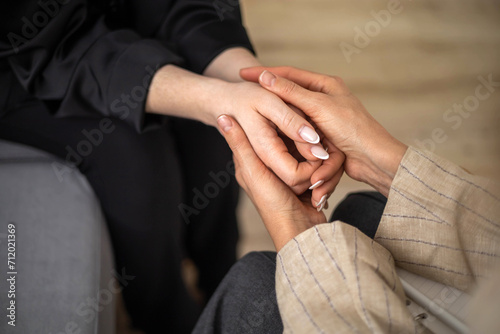 Two woman holding hands concept of support sisterhood care unity and togetherness closeup top view
