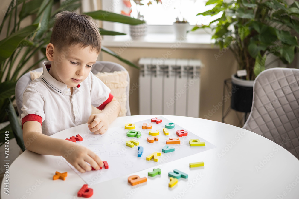 A Caucasian light-haired boy of five years old with blue eyes is putting together a puzzle A Caucasian light-haired boy of five years old with blue eyes is putting together a puzzle