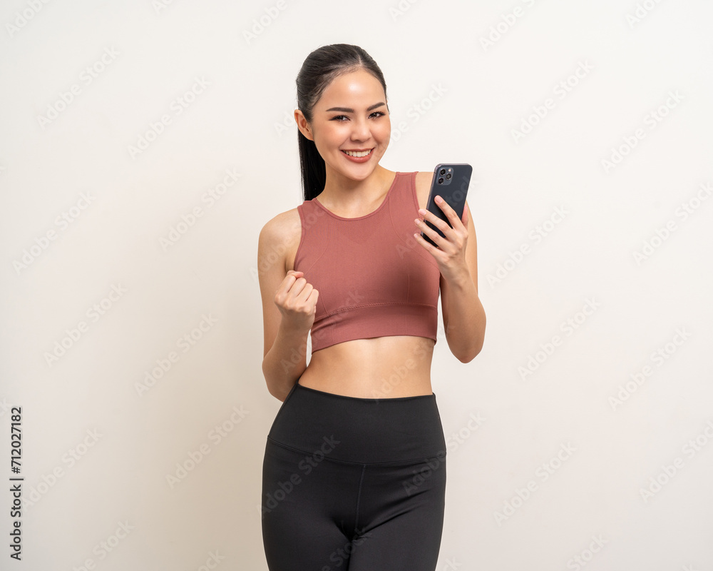 Young beautiful asian woman with sportswear using smartphone on isolated white background. Attractive Portrait latin sporty woman standing pose holding cell phone exercise workout in studio.