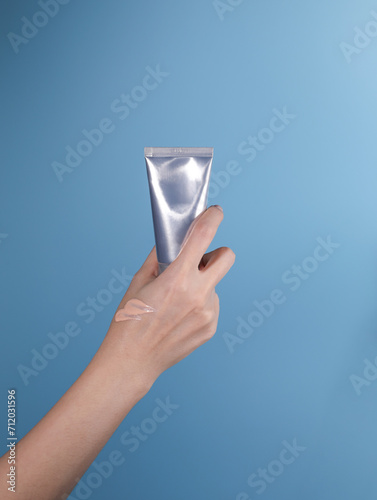 hand holding tube product on blue background