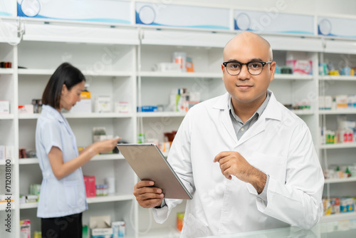 Professional asian man pharmacist checks inventory arrangement of medicine in pharmacy drugstore. Male Pharmacist wearing uniform standing near drugs shelves counter prescription to customers