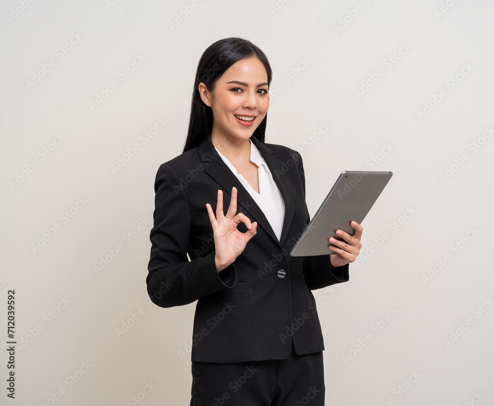 Attractive elegant young asian business woman using digital tablet standing on isolated background. Happy young latin female formal black suit holding tablet gadget working service with customer Attractive elegant young asian business woman using digital tablet standing on isolated background. Happy young latin female formal black suit holding tablet gadget working service with customer