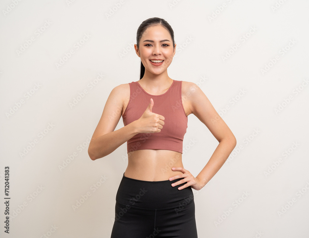Young beautiful smiling asian woman with sportswear showing thumbs up standing on isolated. Happy healthy slim fit and firm latin attractive sporty woman standing pose exercise workout in studio. Young beautiful smiling asian woman with sportswear showing thumbs up standing on isolated. Happy healthy slim fit and firm latin attractive sporty woman standing pose exercise workout in studio.