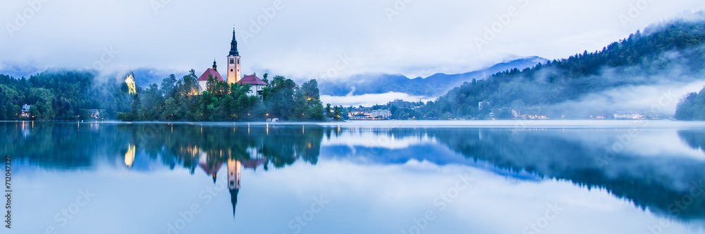 Lake Bled Slovenia with the small island in the middle of the lake and the old church at sunrise with mist over the lake.