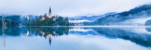 Lake Bled Slovenia with the small island in the middle of the lake and the old church at sunrise with mist over the lake. photo