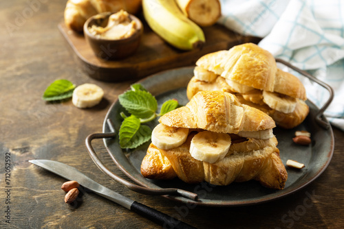Healthy food dessert concept. French pastry. Tasty freshly baked croissants with peanut butter and banana on a rustic background.